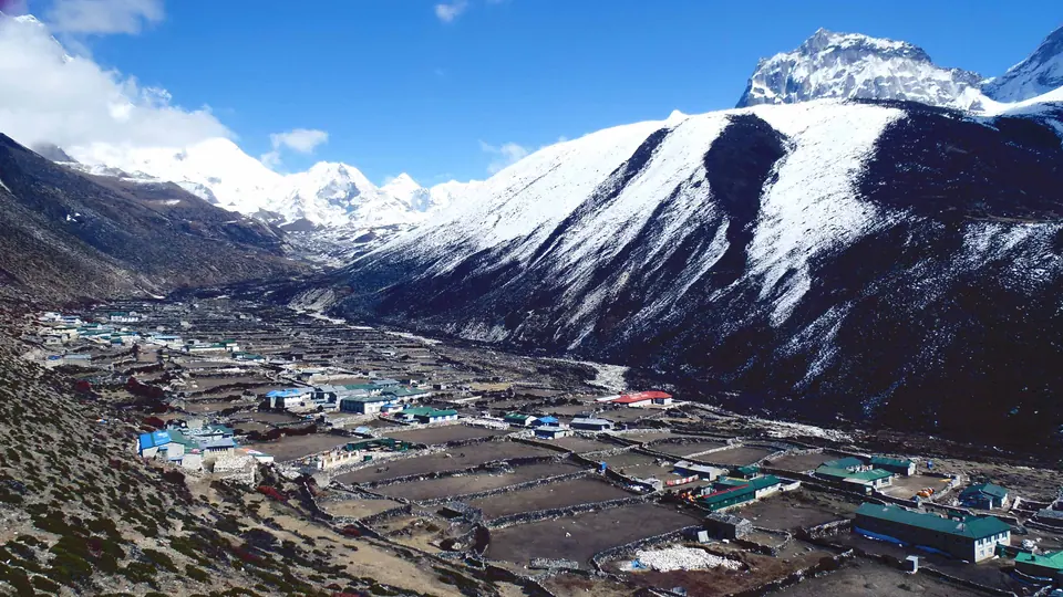 Trekking village in a wide Khumbu valley below snow peaks